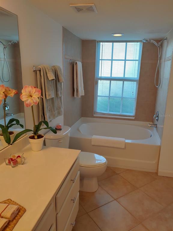 A bathroom features a white vanity, a toilet, and a bathtub with a shower head — 4122 RESIDENCE DR UNIT 102, FORT MYERS, FL