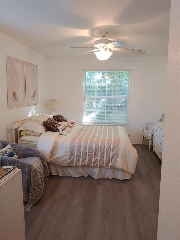 A bedroom with a bed, ceiling fan, window, and wood-look flooring — 4122 RESIDENCE DR UNIT 102, FORT MYERS, FL
