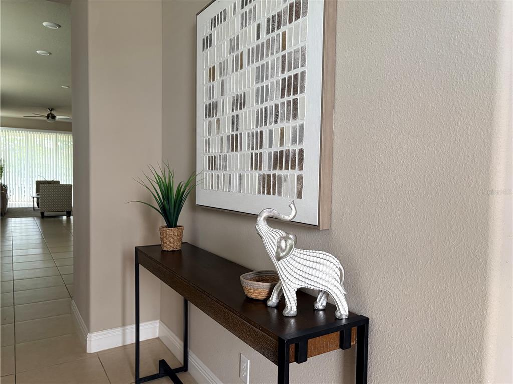 A console table with an elephant figurine and artwork sits in a neutral-toned entryway — 14543 STRATHGLASS DRIVE, HUDSON, FL