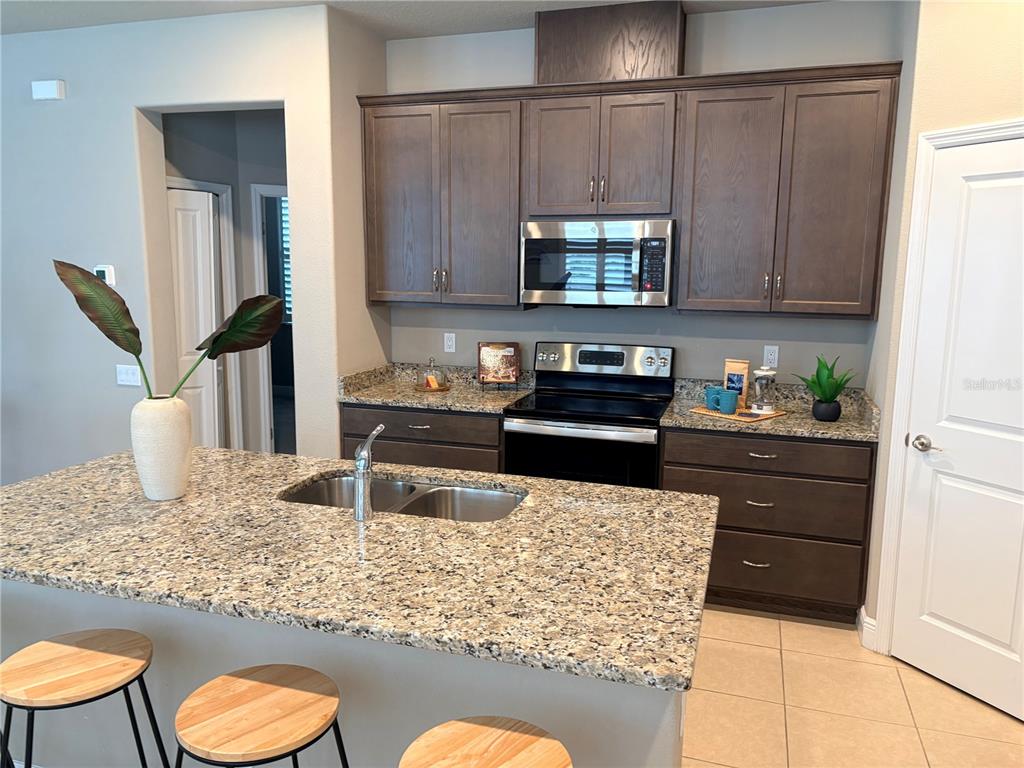 A kitchen features dark wood cabinets, granite countertops, a stainless steel microwave, and a center island — 14543 STRATHGLASS DRIVE, HUDSON, FL