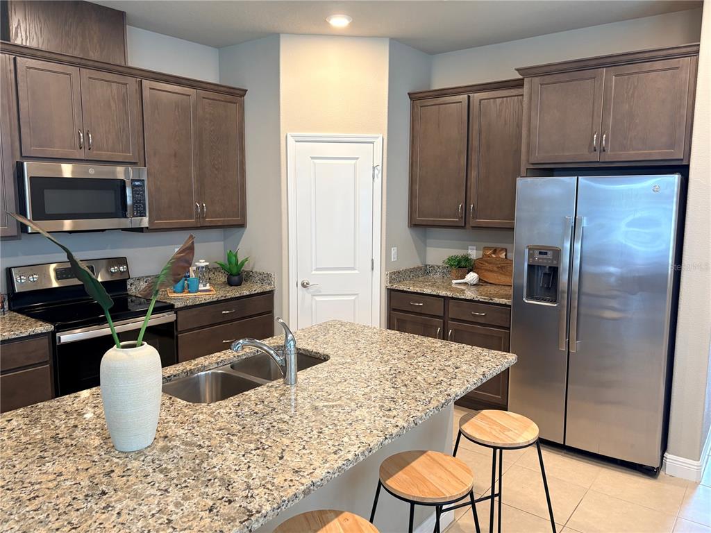 A kitchen features dark wood cabinets, granite countertops, stainless steel appliances, and a central island — 14543 STRATHGLASS DRIVE, HUDSON, FL