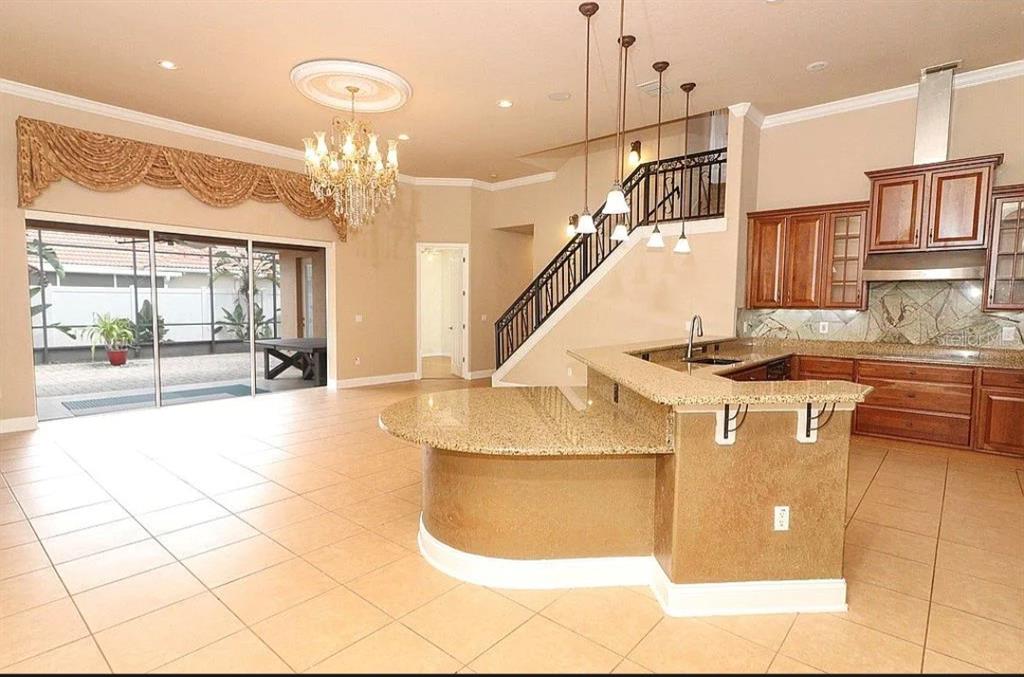 A kitchen with granite countertops and a breakfast bar overlooks an open living area — 8950 TUSCAN VALLEY PLACE, ORLANDO, FL
