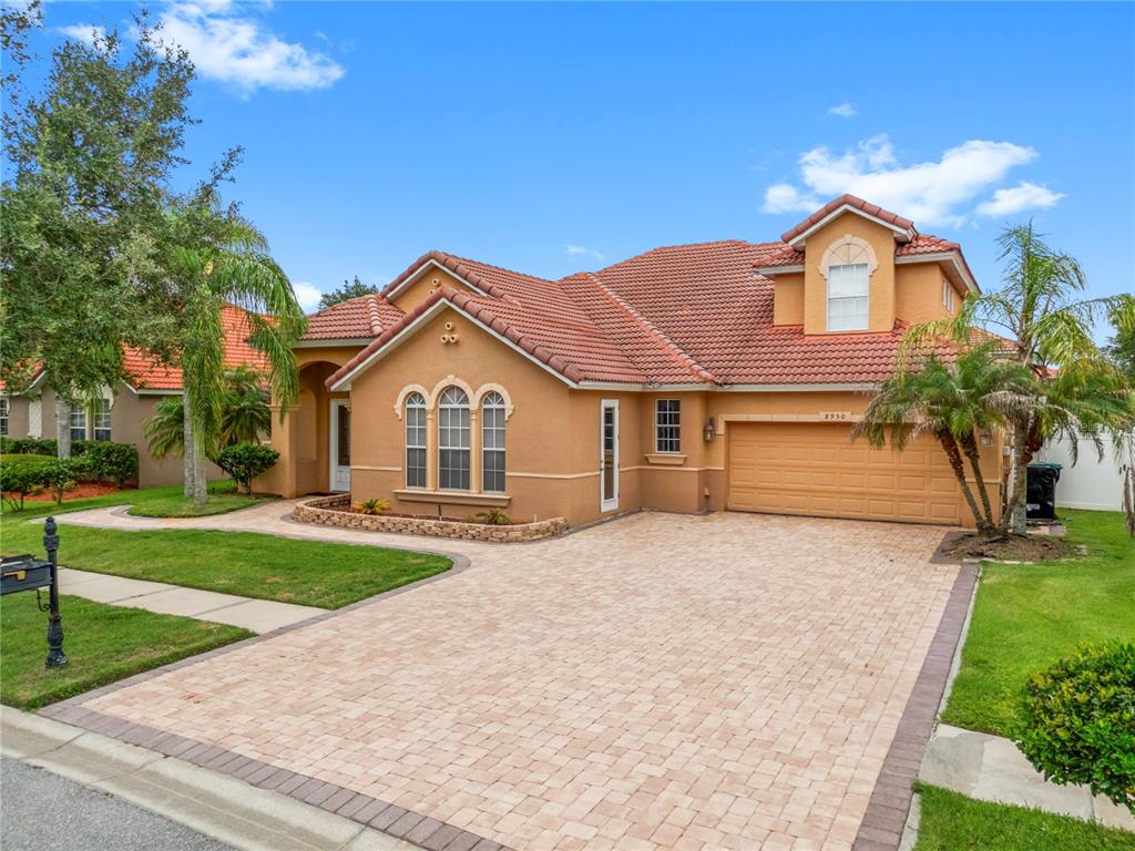 A single-story stucco house with a tiled roof, a paved driveway, and a two-car garage — 8950 TUSCAN VALLEY PLACE, ORLANDO, FL