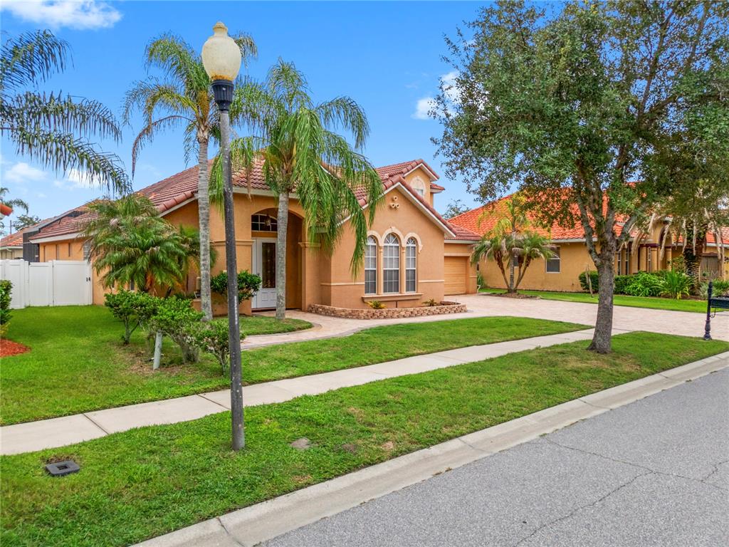 A single-story stucco house with a tile roof and palm trees in the front yard — 8950 TUSCAN VALLEY PLACE, ORLANDO, FL