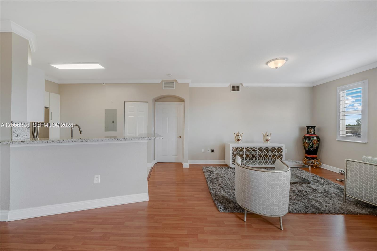 An open-concept living area features wood-look flooring, a kitchen peninsula, and a gray area rug — 9021 SW 94th St # 509, Miami FL 33176, MIAMI, FL