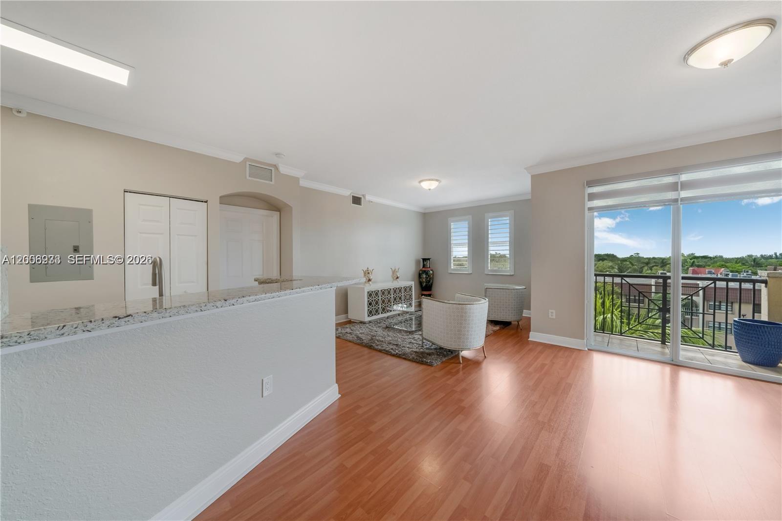 A living room features wood-look flooring, a granite-topped breakfast bar, and a balcony with views — 9021 SW 94th St # 509, Miami FL 33176, MIAMI, FL