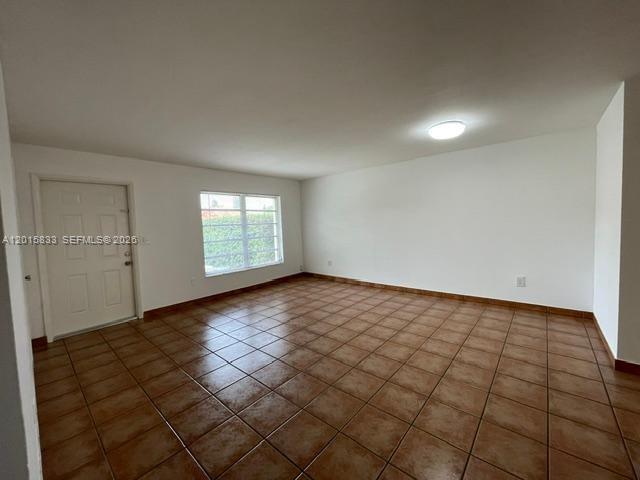 An empty room features white walls, a single window, and brown tiled flooring — 10112 SW 20th St, Miami FL 33165, MIAMI, FL