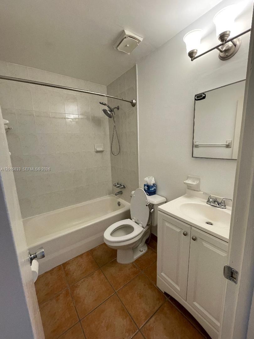 A bathroom features a tiled tub-shower combination, a white vanity, and terracotta-colored floor tiles — 10112 SW 20th St, Miami FL 33165, MIAMI, FL
