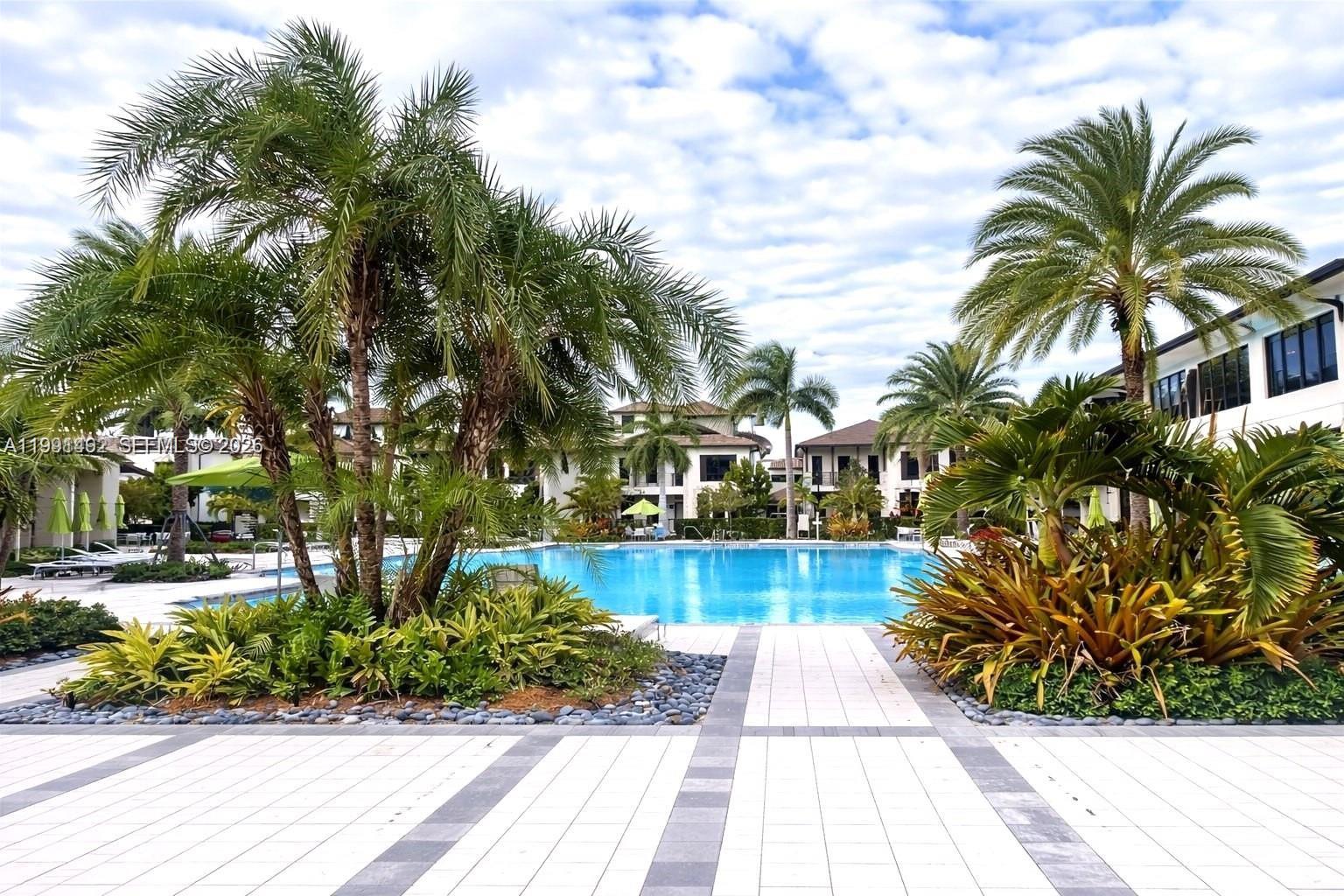 A swimming pool is surrounded by palm trees and multi-story residential buildings — 8001 NW 41 St # 409, Doral FL 33166, DORAL, FL