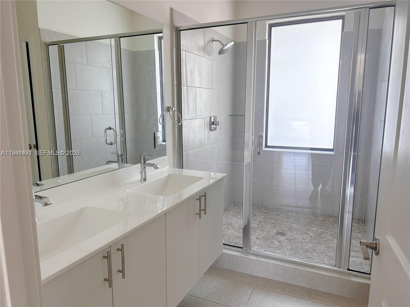 A modern bathroom features a double vanity with white cabinets and a glass-enclosed walk-in shower — 8001 NW 41 St # 409, Doral FL 33166, DORAL, FL