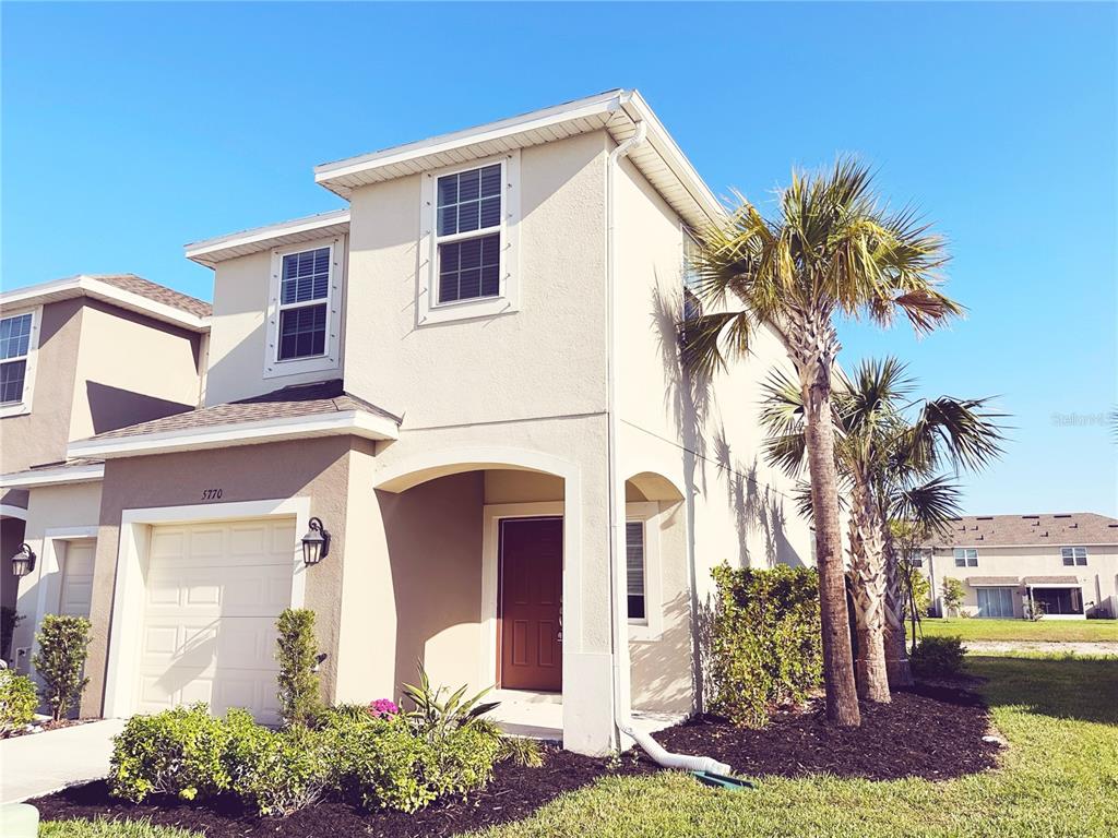 A two-story stucco house with a garage, a front porch, and palm trees — 5770 WINDY BAY TERRACE, NOKOMIS, FL