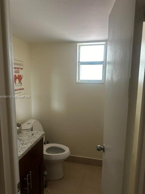 A small bathroom features a white toilet, a dark wood vanity, and a window — MIAMI, FL