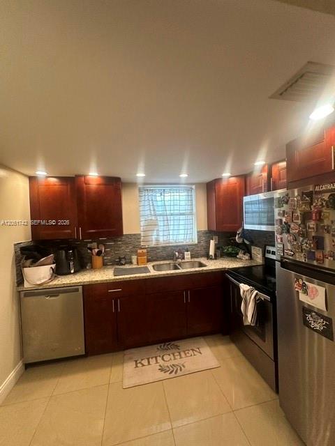 A kitchen features dark wood cabinets, stainless steel appliances, and light-colored tile flooring — MIAMI, FL