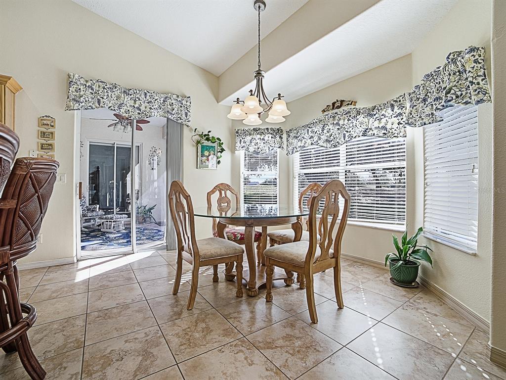 A dining area features a glass-topped table, four wooden chairs, tile flooring, and sliding doors — 24239 BELLE MEDE DRIVE, LEESBURG, FL