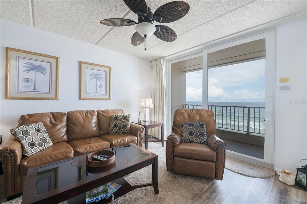 A living room features a leather sofa and recliner with a view of the ocean — 4453 S ATLANTIC AVENUE UNIT 604, PONCE INLET, FL