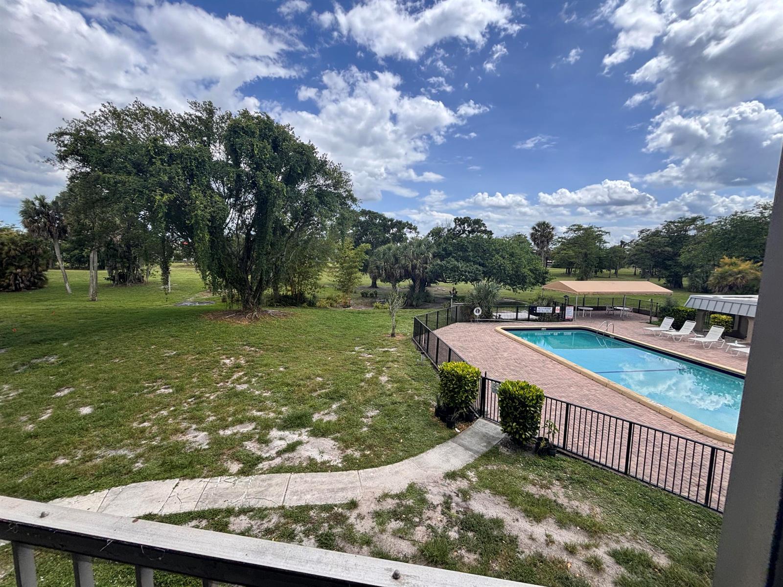 An elevated view of a swimming pool area with a grassy lawn and large trees — 6100 S Falls Circle Drive # 204, Lauderhill FL 33319, LAUDERHILL, FL