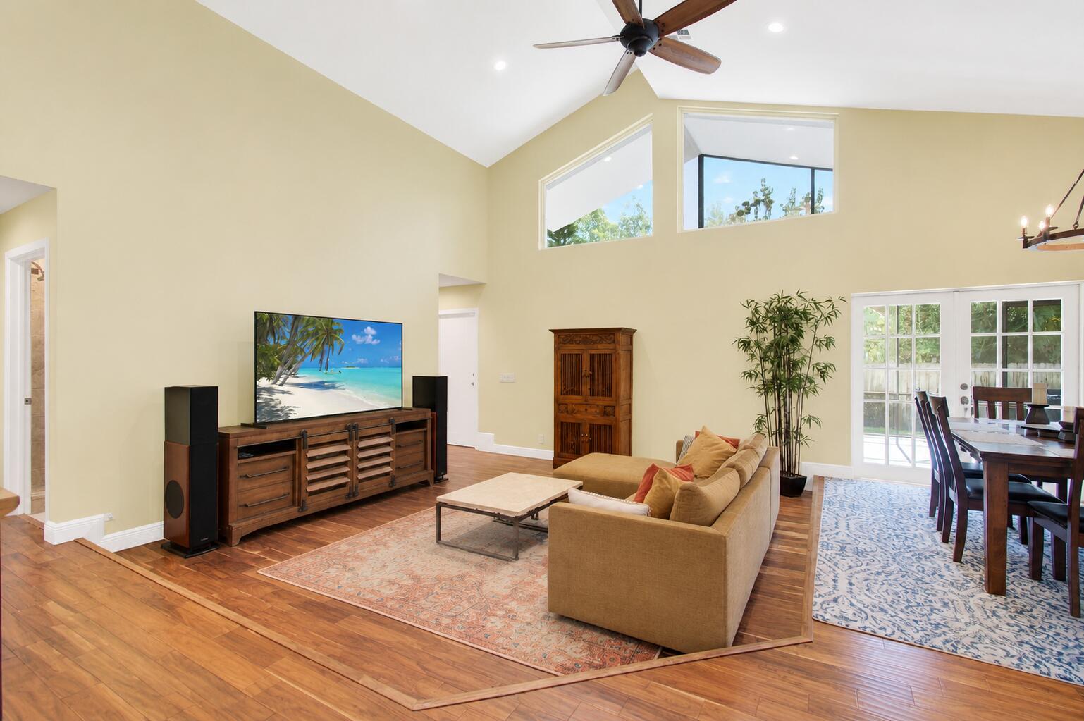 A living room with vaulted ceilings, hardwood floors, a television console, and a dining area — 3001 Eagle Drive, Delray Beach FL 33444, DELRAY BEACH, FL