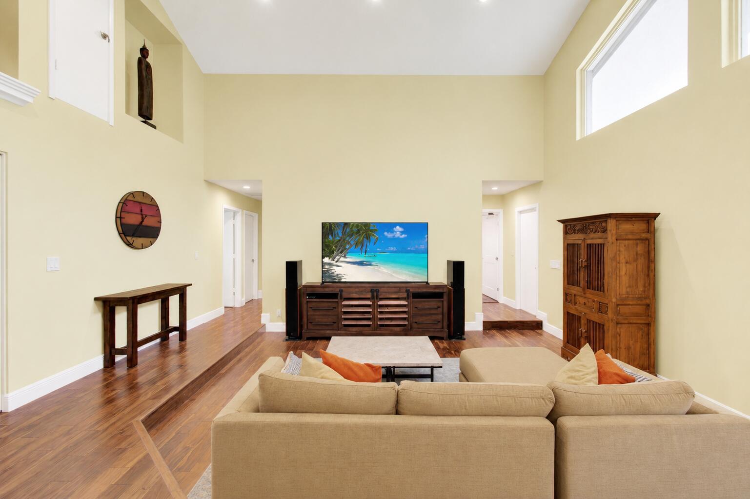 A living room with high ceilings, light yellow walls, hardwood floors, and a sectional sofa — 3001 Eagle Drive, Delray Beach FL 33444, DELRAY BEACH, FL