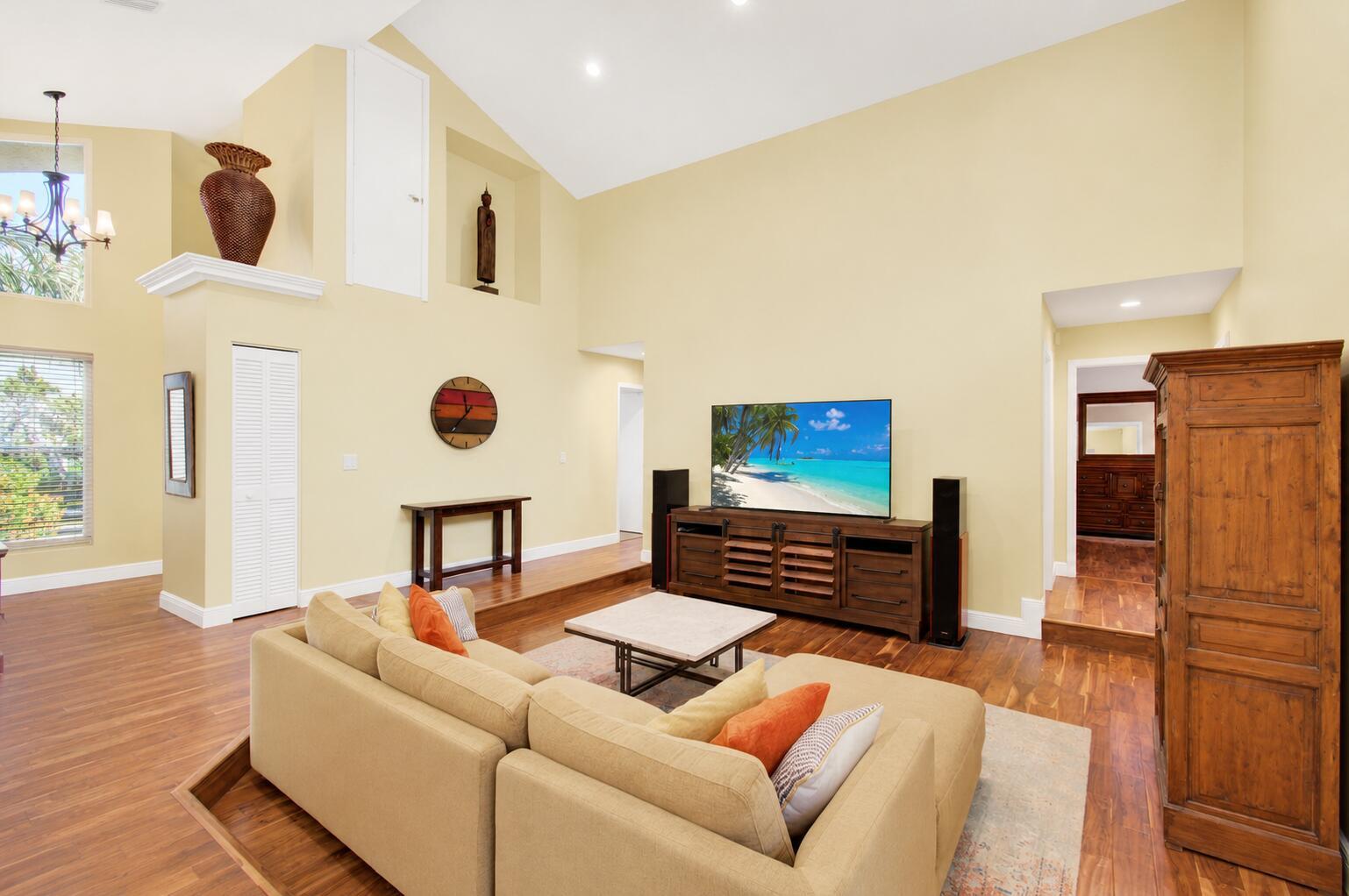 A living room with vaulted ceilings, hardwood floors, a sectional sofa, and a television console — 3001 Eagle Drive, Delray Beach FL 33444, DELRAY BEACH, FL