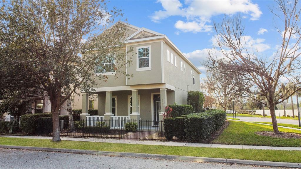 A two-story house with a front porch, fenced yard, and light green stucco exterior — 9306 MIRA VALLE LANE, WINTER GARDEN, FL