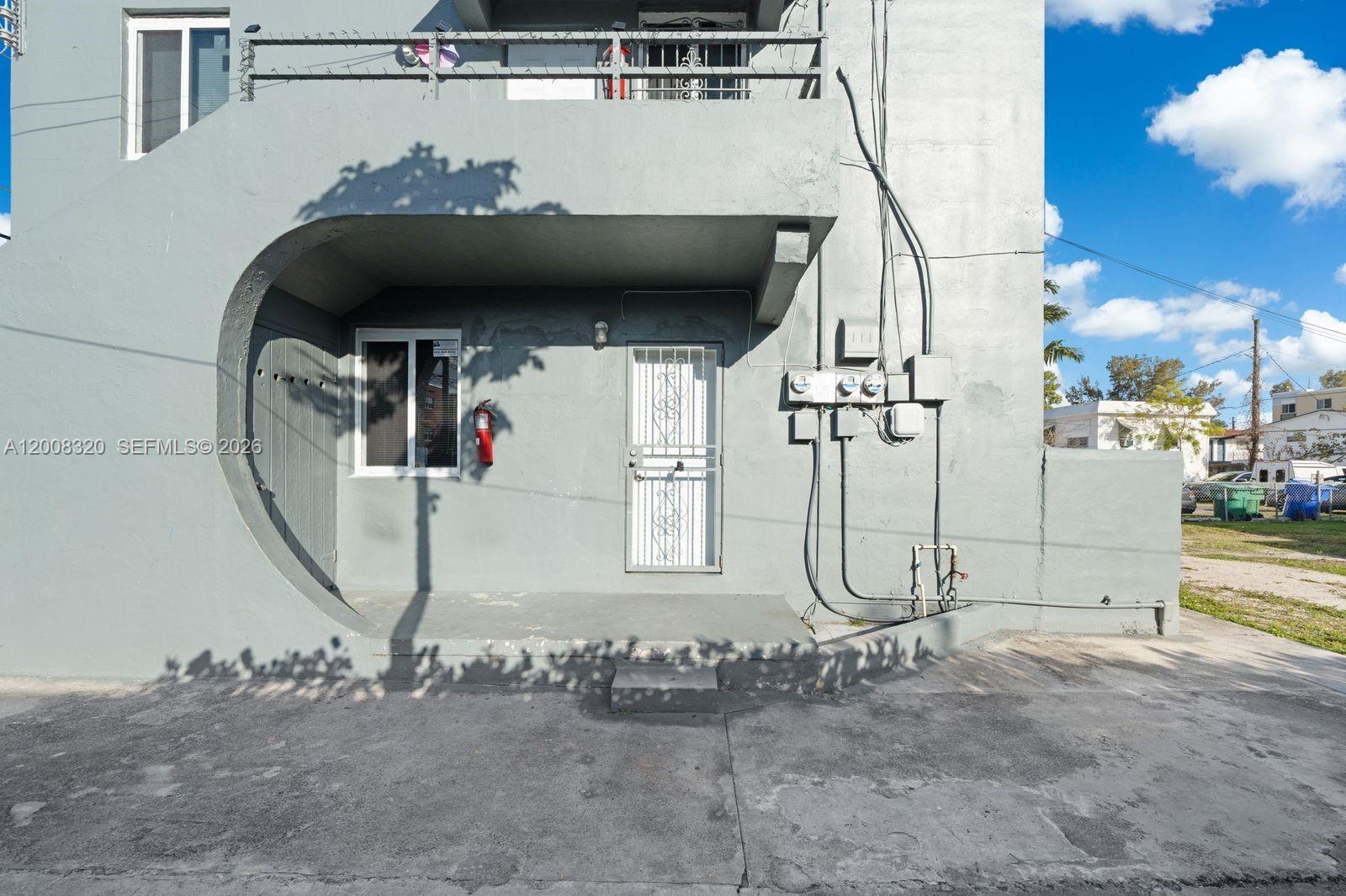 The exterior of a gray concrete building features a recessed entryway with a security door — 842 SW 3rd St, Miami FL 33130, MIAMI, FL