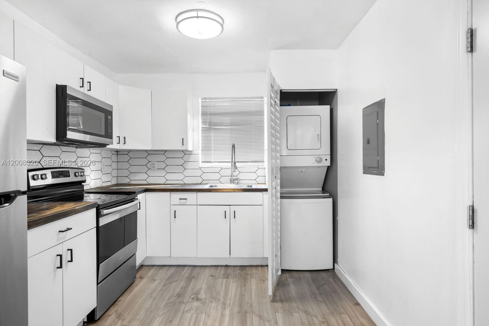 A kitchen features white cabinets, stainless steel appliances, wood-look countertops, and a stacked laundry unit — 842 SW 3rd St, Miami FL 33130, MIAMI, FL