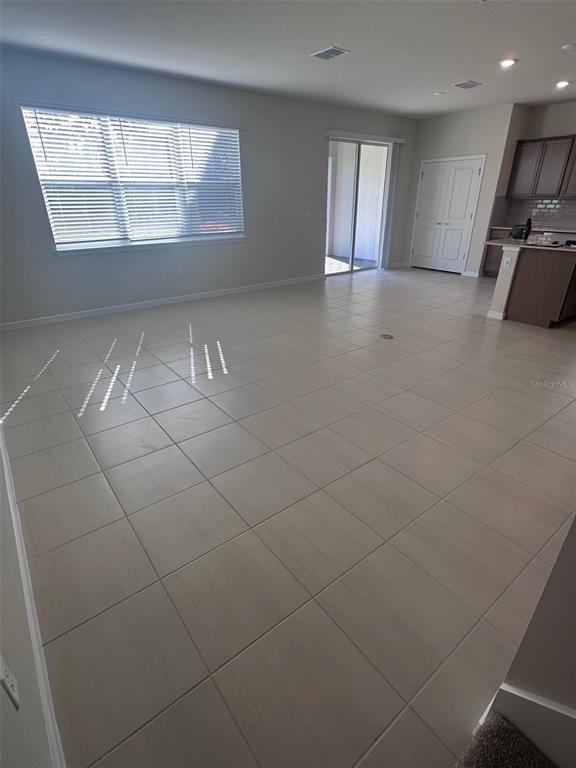 An open-concept living area features light-colored tile flooring, a large window, and a sliding door — 17539 SAW PALMETTO AVENUE, CLERMONT, FL