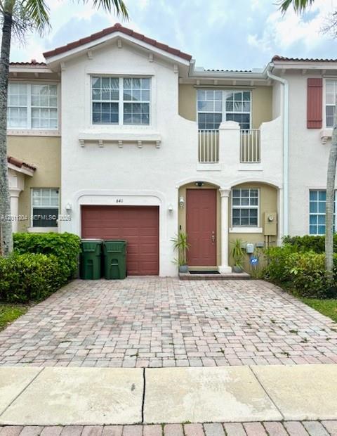A two-story townhouse with a paver driveway, a single-car garage, and a red front door — 641 NE 21st Ter, Homestead FL 33033, HOMESTEAD, FL