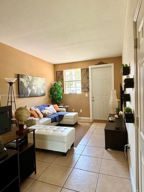 A living room features a white sectional sofa, a matching ottoman, and tiled flooring — 641 NE 21st Ter, Homestead FL 33033, HOMESTEAD, FL