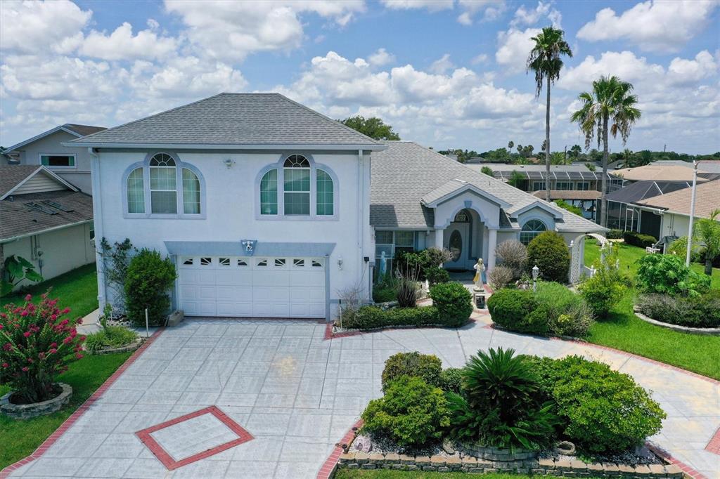A two-story white house with a multi-car garage and a paved driveway with landscaping — 12 CLOVERDALE COURT S, PALM COAST, FL
