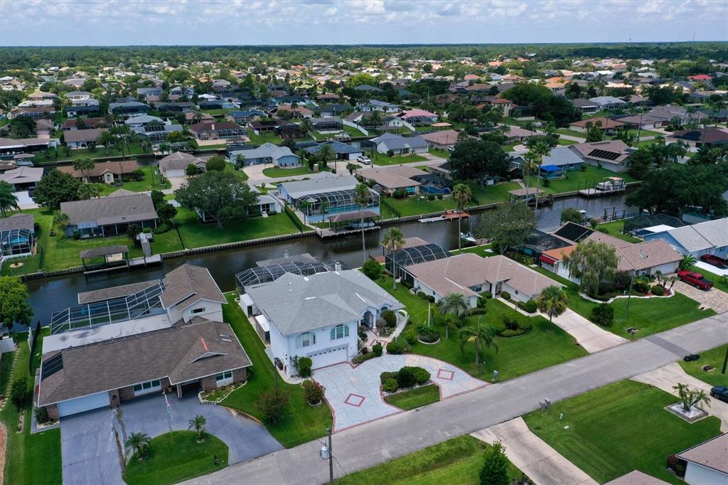 An aerial view shows a residential neighborhood with houses, swimming pools, and a canal — 12 CLOVERDALE COURT S, PALM COAST, FL