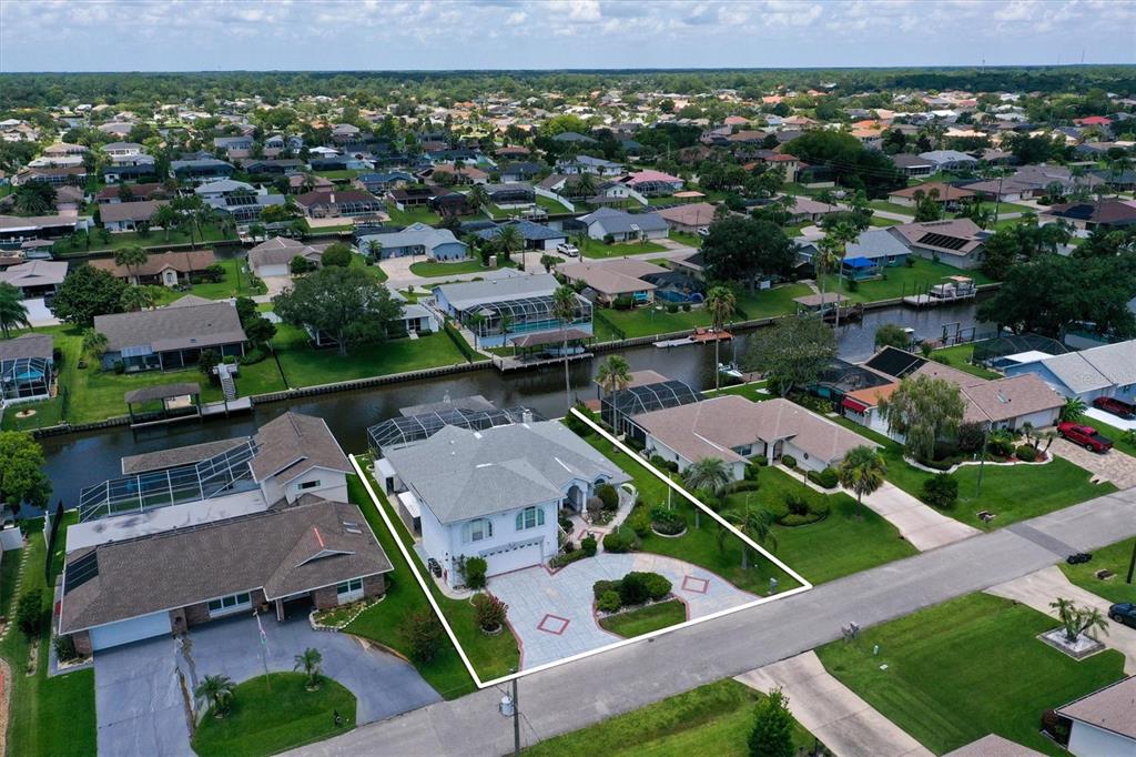An aerial view shows a light-colored house with a paved driveway and a canal backyard — 12 CLOVERDALE COURT S, PALM COAST, FL
