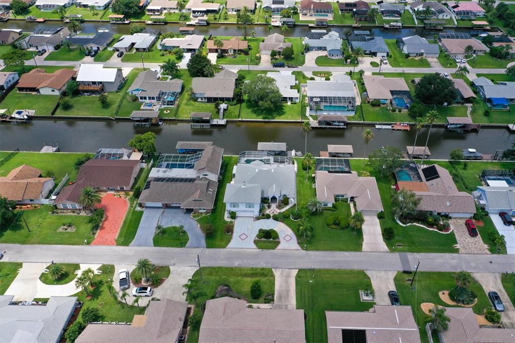 An aerial view shows residential houses with swimming pools and boat docks along a canal — 12 CLOVERDALE COURT S, PALM COAST, FL