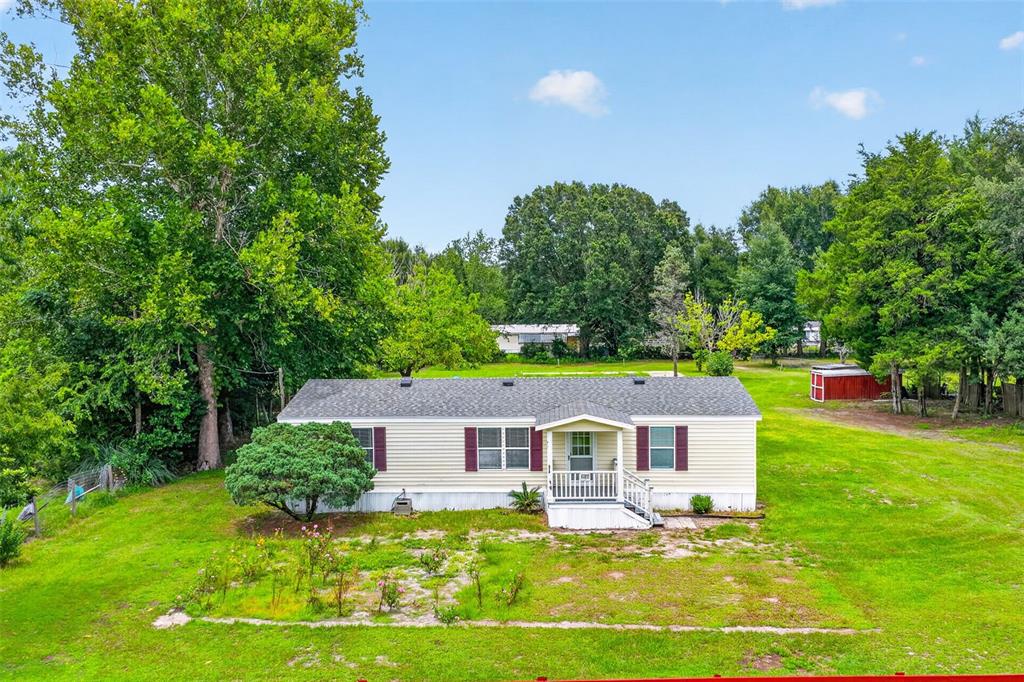 A single-story manufactured home with light siding and red shutters sits on a grassy lot — 2535 SE 172ND STREET, SUMMERFIELD, FL