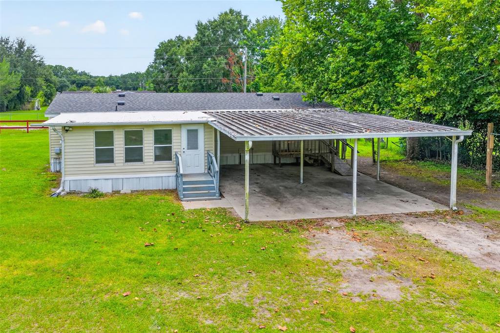 A single-story house with light yellow siding, a metal carport, and a small front porch — 2535 SE 172ND STREET, SUMMERFIELD, FL