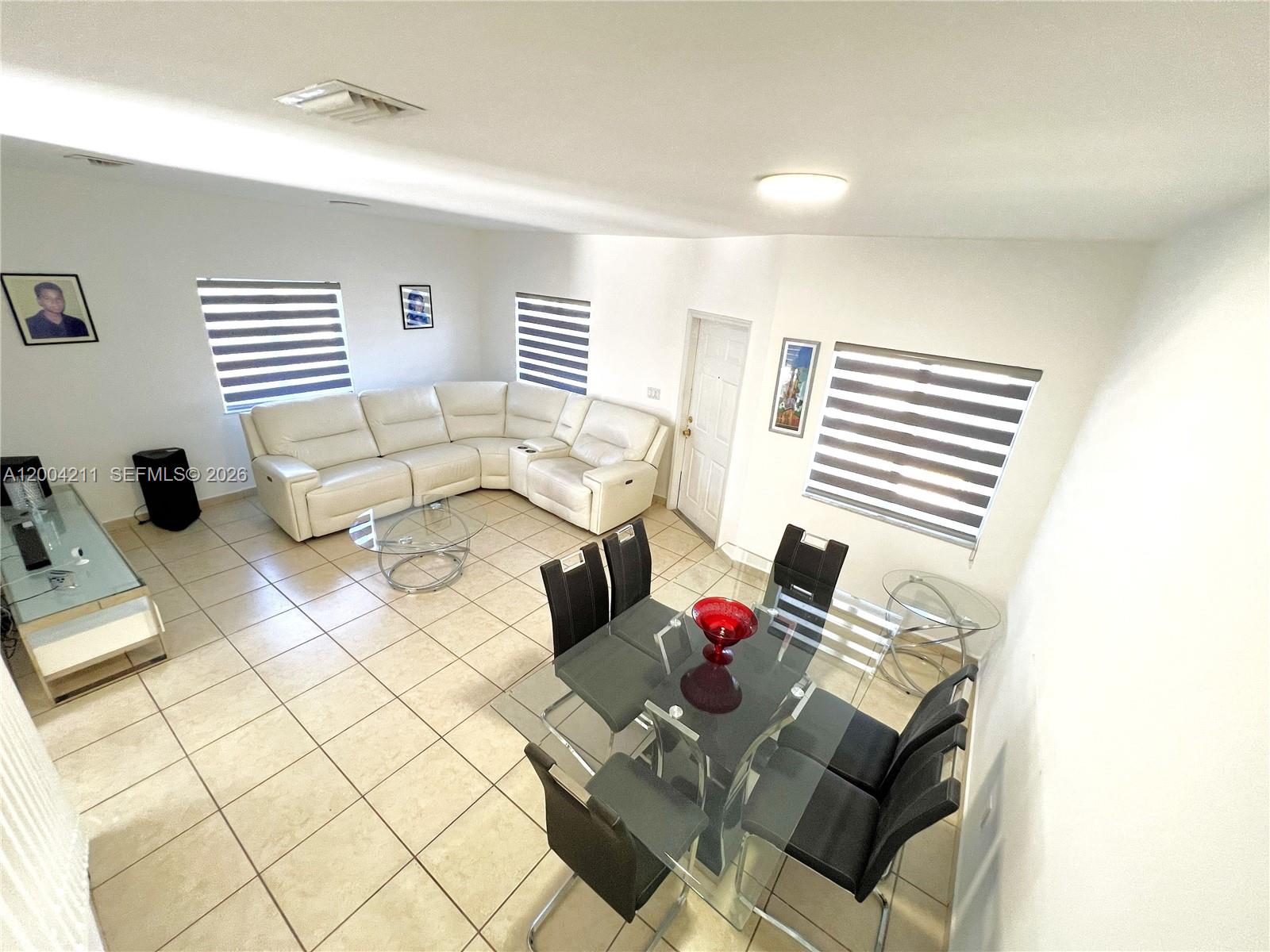 A living and dining area features white tile floors, a sectional sofa, and glass tables — 2914 SE 15th Ter, Homestead FL 33035, HOMESTEAD, FL