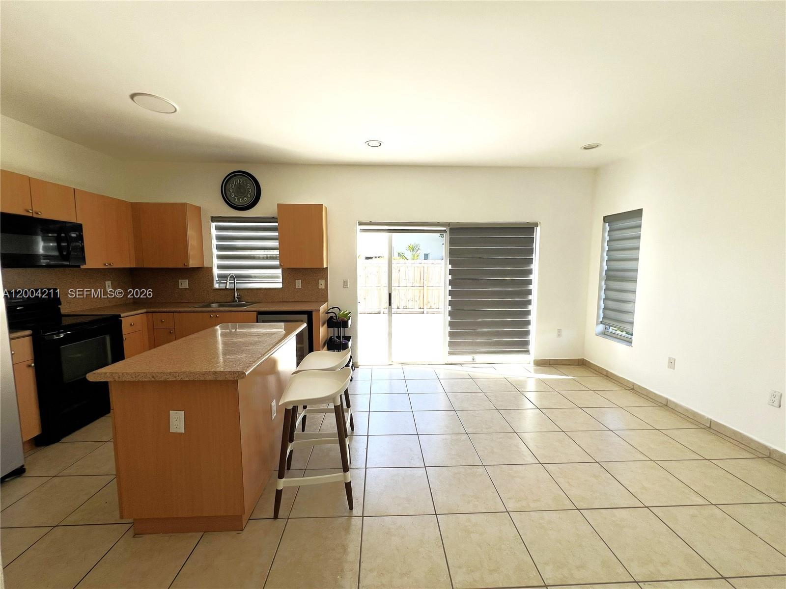 A kitchen with light wood cabinets, a granite island, and tile flooring opens to a patio — 2914 SE 15th Ter, Homestead FL 33035, HOMESTEAD, FL