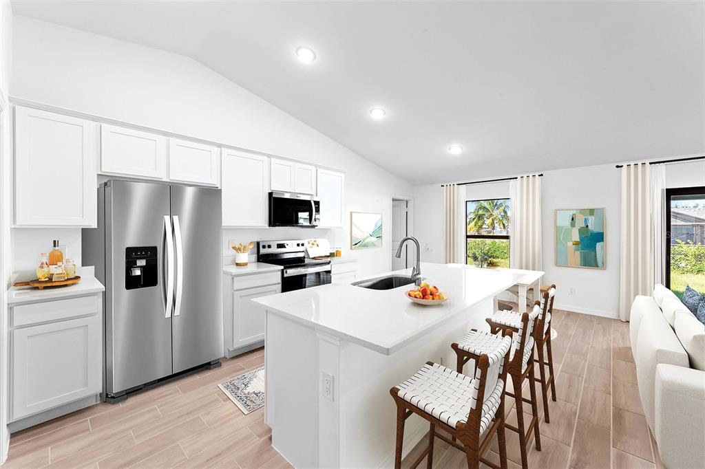 A modern kitchen features white cabinetry, stainless steel appliances, a central island, and tile flooring — 415 STARBORN STREET, PORT CHARLOTTE, FL