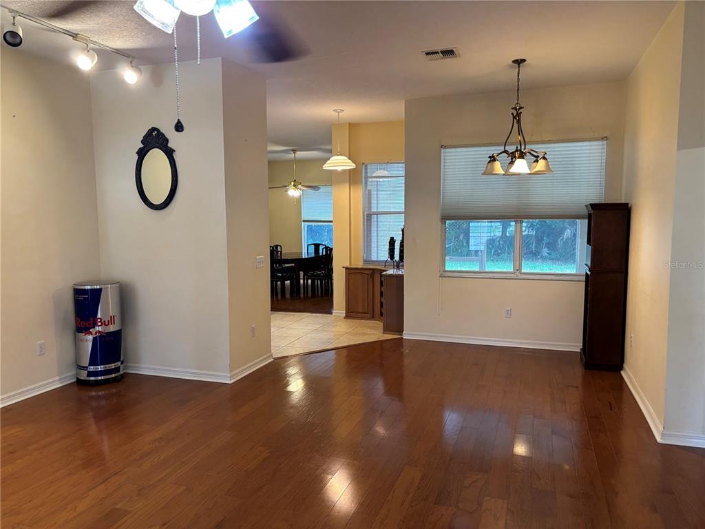 A living room with hardwood floors leads to a dining area with tile flooring — 5 BIRD HAVEN PLACE, PALM COAST, FL