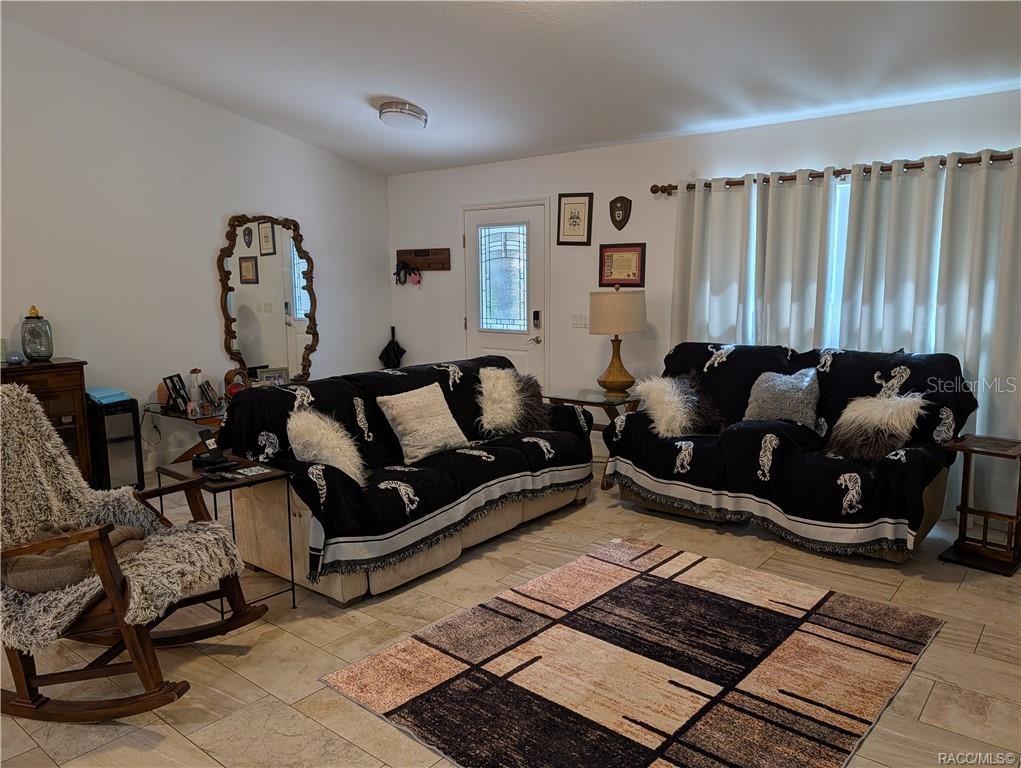 A living room features tiled floors, two sofas with patterned throws, and a rocking chair — 9711 S BERKSHIRE AVENUE, INVERNESS, FL