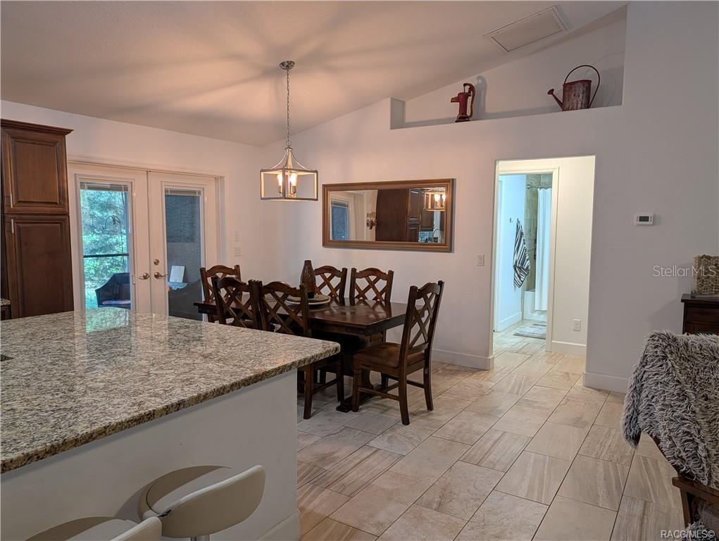 A dining area with a wooden table, chairs, and a pendant light near a kitchen — 9711 S BERKSHIRE AVENUE, INVERNESS, FL