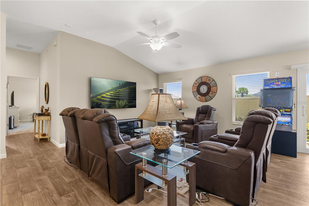 A living room features brown leather recliners, a glass-topped end table, and a wall-mounted television — 4295 FREDDA TERRACE, THE VILLAGES, FL