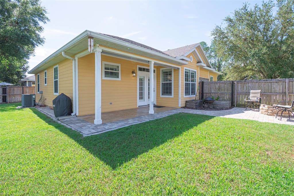 A yellow house with a covered patio, brick pavers, and a fenced backyard — 14274 NW 9TH ROAD, NEWBERRY, FL