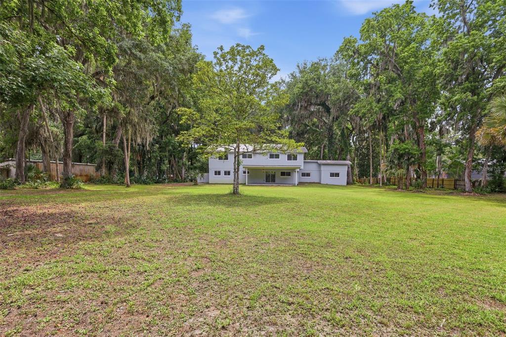 A two-story house with a large backyard surrounded by mature trees and Spanish moss — 555 WILDWOOD DRIVE, NEW SMYRNA BEACH, FL