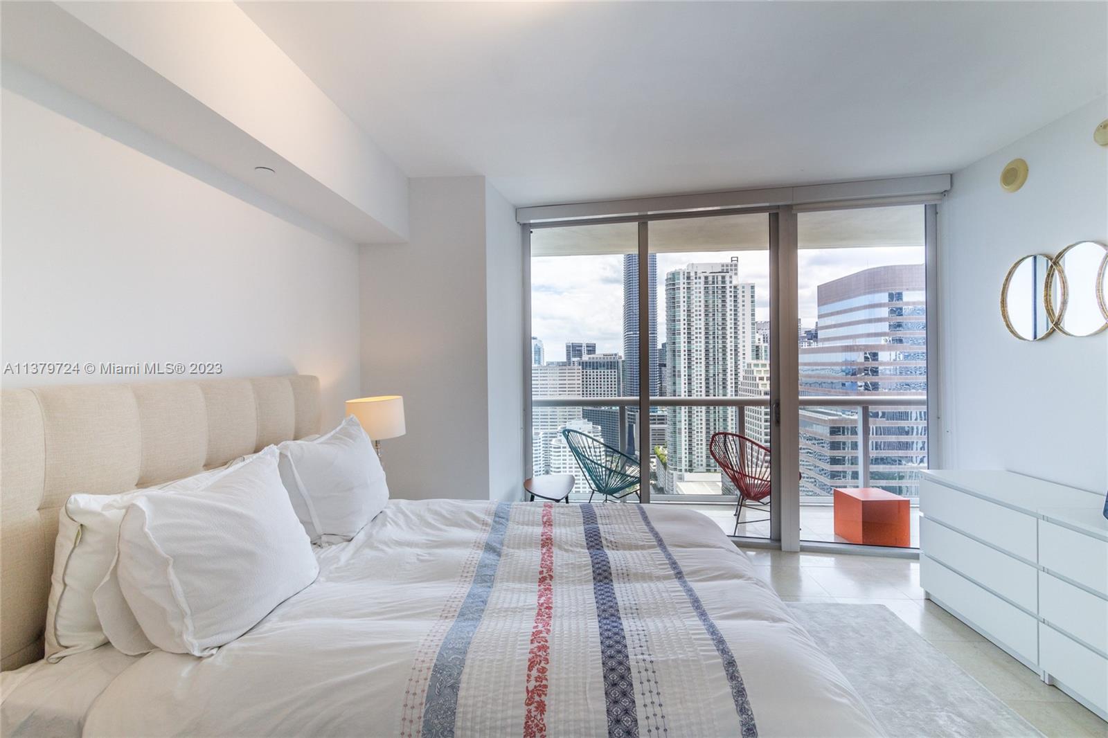 A modern bedroom features a large bed, white dresser, and a balcony with city views — 495 Brickell Ave # 3603, Miami FL 33131, MIAMI, FL