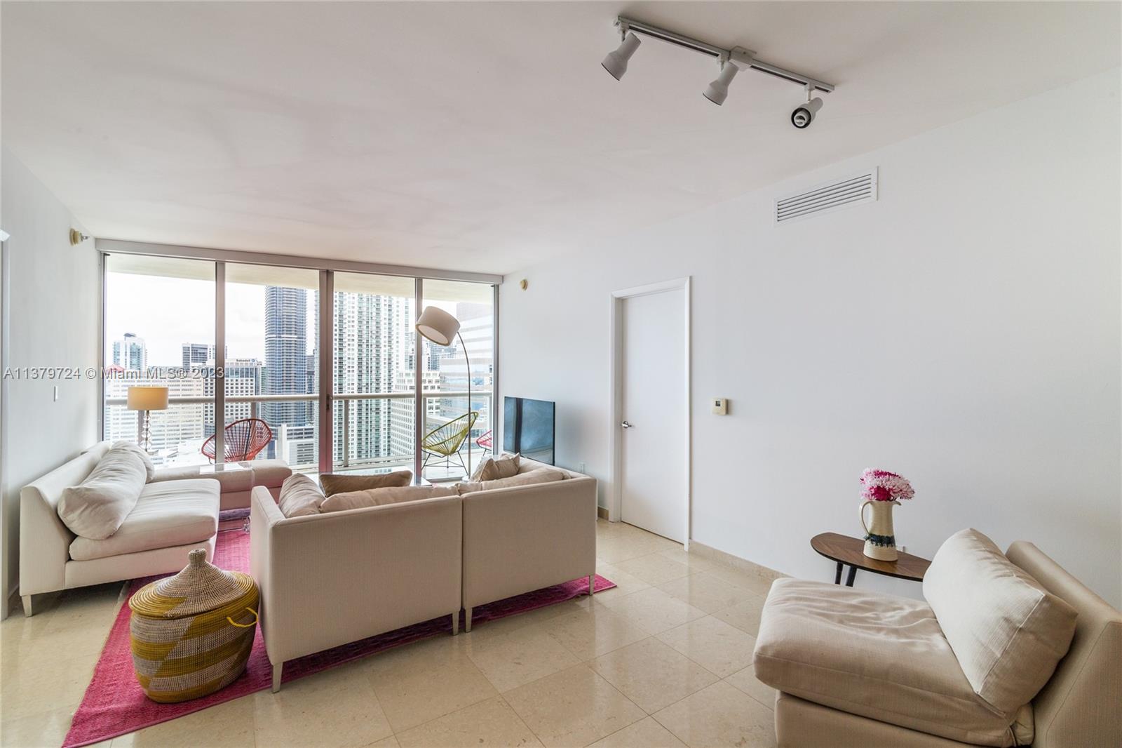 A living room features light-colored furniture, a pink area rug, and floor-to-ceiling windows with city views — 495 Brickell Ave # 3603, Miami FL 33131, MIAMI, FL