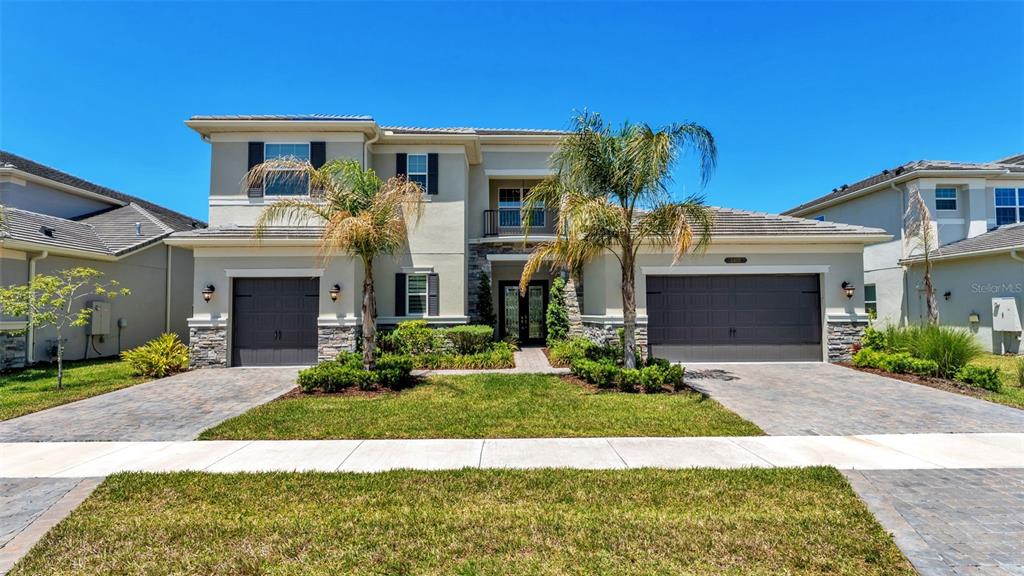 A two-story suburban house features a stone facade, two garages, and two palm trees — 3405 JUNIPER SPRINGS STREET, WESLEY CHAPEL, FL