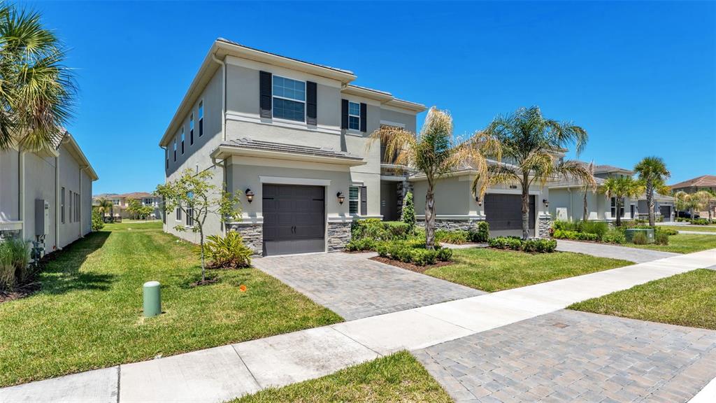 A two-story suburban house with a gray garage, stone accents, and palm trees — 3405 JUNIPER SPRINGS STREET, WESLEY CHAPEL, FL