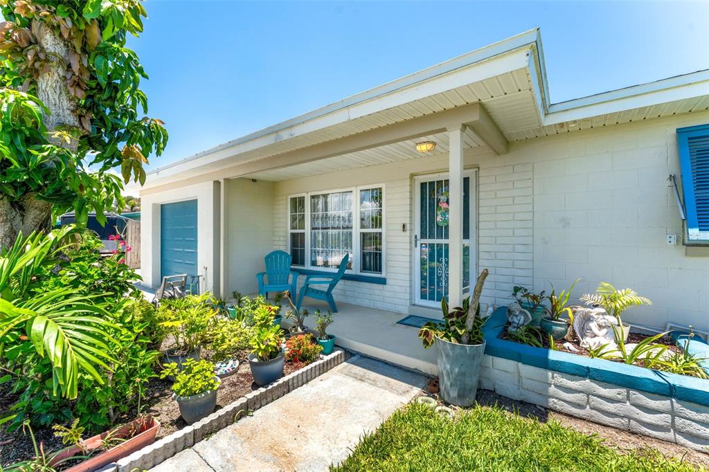 A single-story house exterior features a covered porch, blue shutters, and a landscaped front yard — 341 W DOVER STREET, SATELLITE BEACH, FL