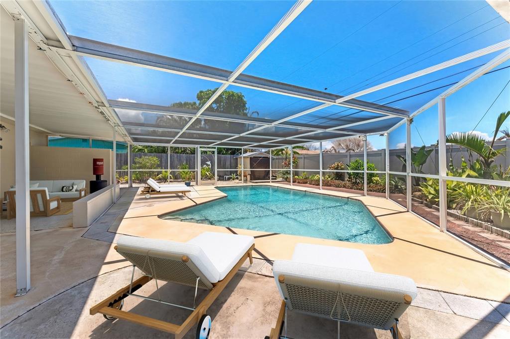 A screened-in pool patio features lounge chairs, a concrete deck, and a fenced backyard — 341 W DOVER STREET, SATELLITE BEACH, FL